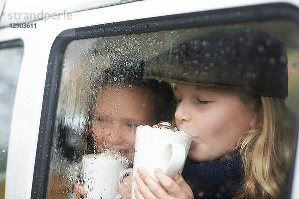 Mädchen trinken heiße Schokolade im Wohnmobil