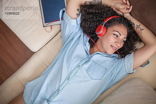 Frau hört zu Hause Musik auf einem digitalen Tablet