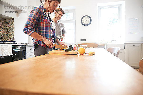 Ehepaar schneidet frisches Obst am Küchentisch in Scheiben