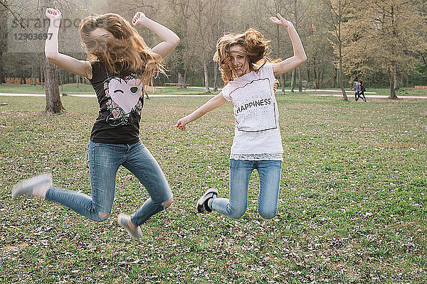 Glückliche Freundinnen springen im Park vor Freude