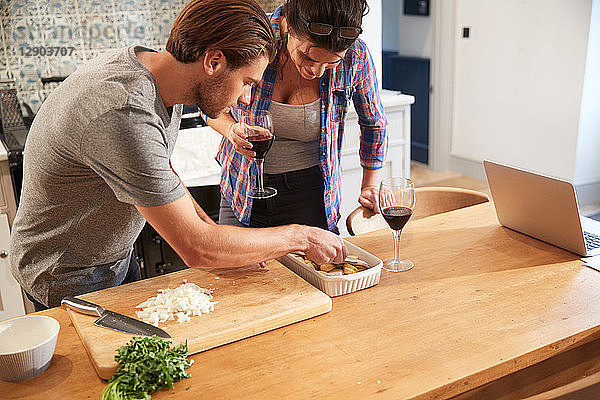 Ehepaar legt Kartoffeln in Bratschüssel am Küchentisch