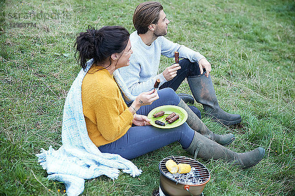 Ehepaar sitzt auf einem ländlichen Feld und grillt