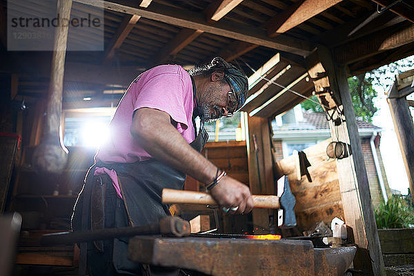 Der Schmied arbeitet in seiner Schmiede