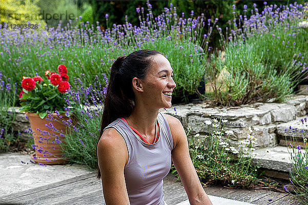 Frau praktiziert Yoga im Garten  macht eine Pause auf der Terrasse