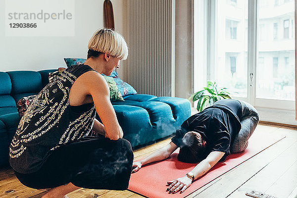 Frau unterrichtet Freundin Yoga zu Hause