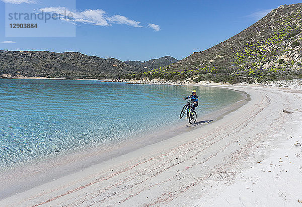 Radfahrer im Wheelie am Strand  Villasimius  Sardinien  Italien