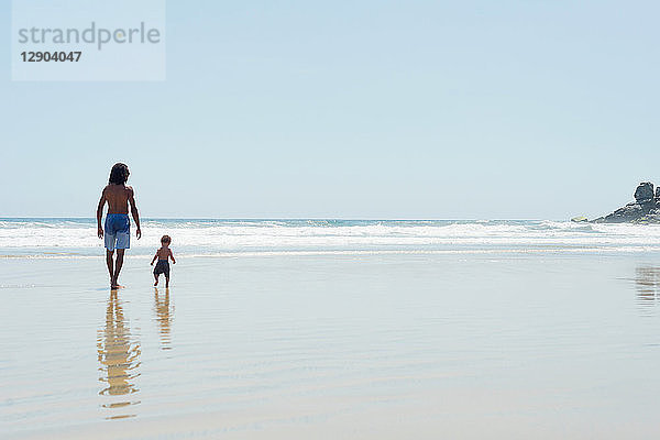 Vater und Sohn gehen am Strand spazieren