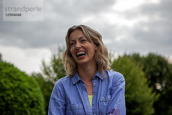 Reife Frau lacht im Garten  Kopf- und Schulterporträt