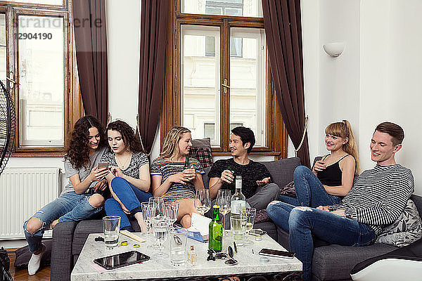 Gruppe erwachsener männlicher und weiblicher Freunde  die auf dem Sofa sitzen  plaudern und trinken