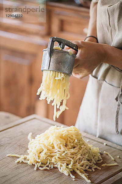 Frau benutzt Kartoffelpresse zur Zubereitung von Gnocchi