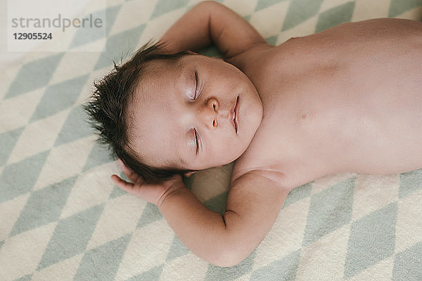 Portrait of a newborn baby boy lying on a blanket with closed eyes