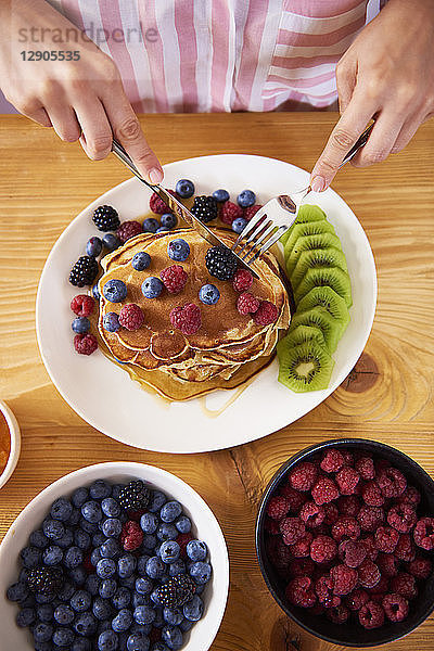 Woman eating pancakes with berries for breakfast