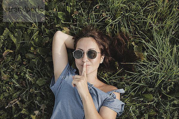 Portrait of smiling woman wearing sunglasses lying in grass