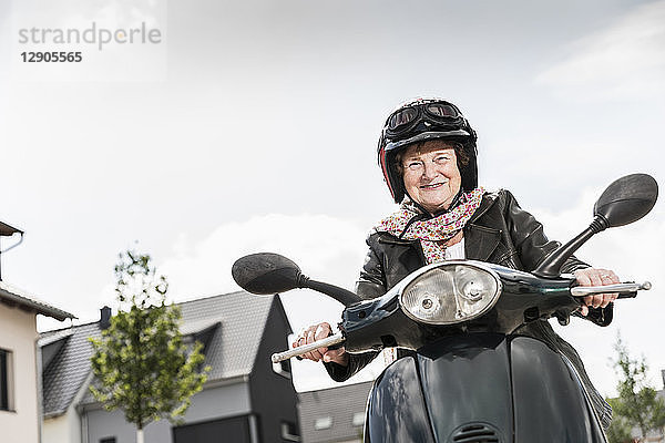 Active senior lady riding motor scooter in the city