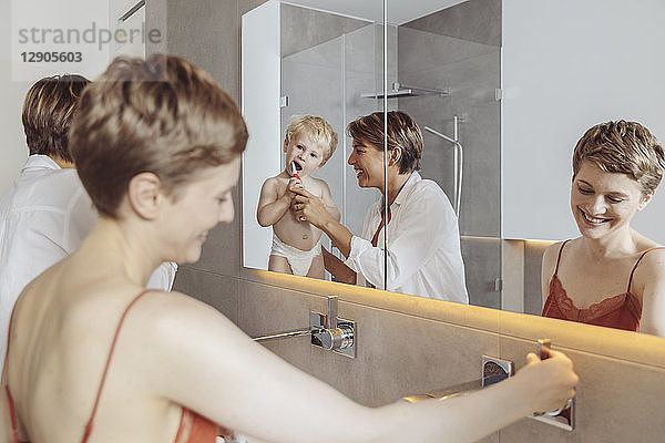 Lesbian couple and their little son getting ready for their day in the bathroom