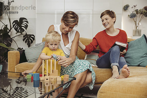 Two mothers learning and playing with their child at home