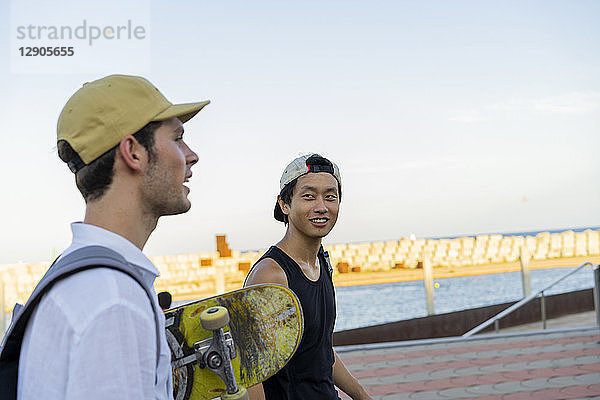 Two young men with skateboard on the move talking