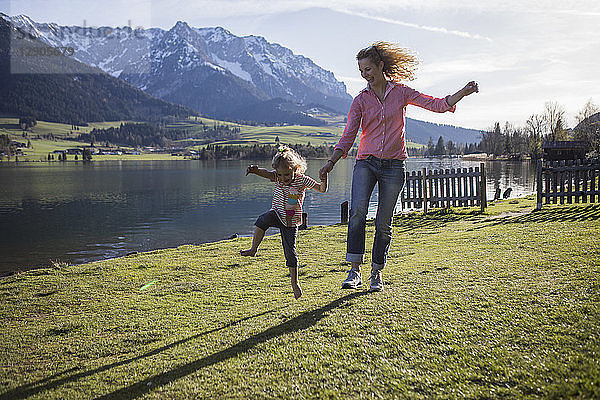 Austria  Tyrol  Walchsee  carefree mother and daughter jumping at the lake