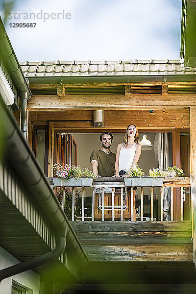 Smiling couple standing on balcony at home