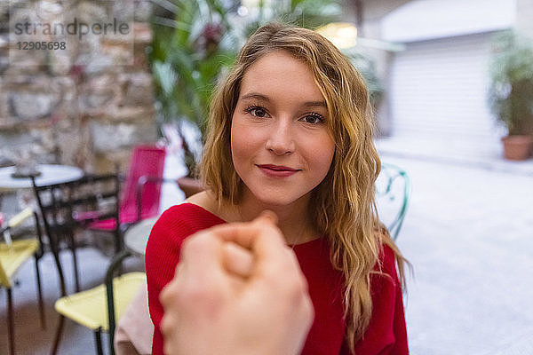 Portrait of young woman holding hands at pavement cafe