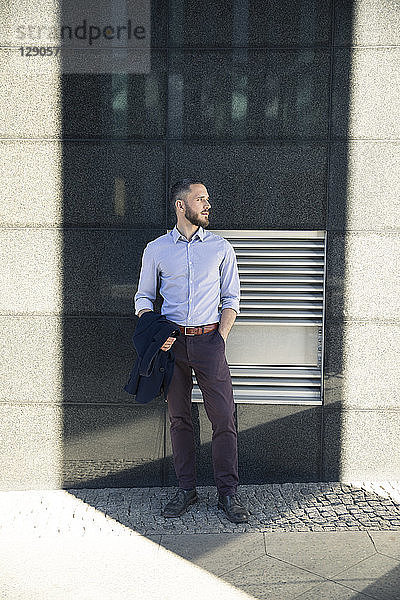 Businessman standing outdoors looking sideways