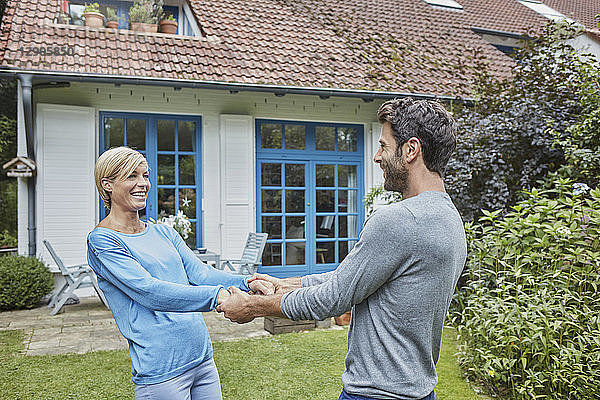 Happy couple dancing in front of their home