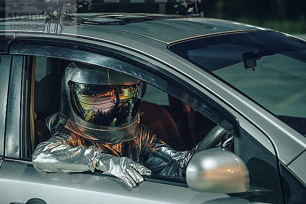 Spaceman sitting in car at night
