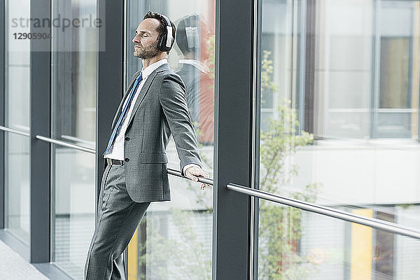 Portrait of businessman with eyes closed listening music with headphones