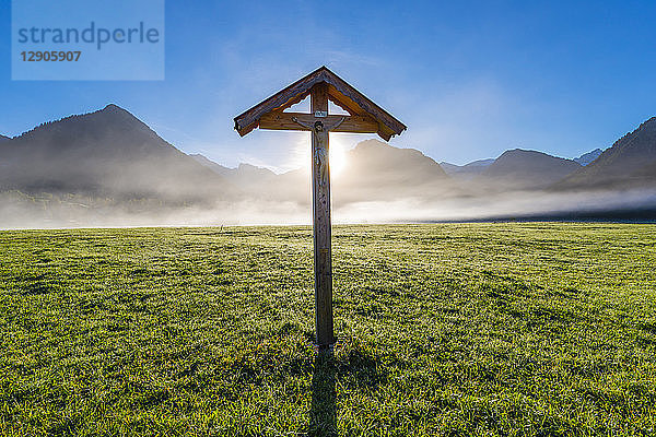 Germany  Bavaria  Allgaeu  Allgaeu Alps  Loretto meadow near Oberstdorf  field cross against morning sun