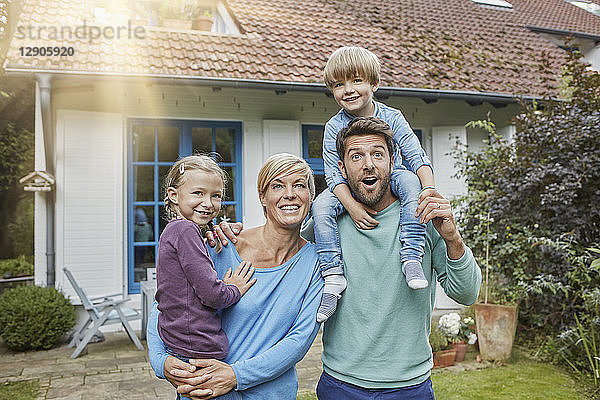 Portrait of happy family with two kids in front of their home