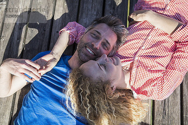 Happy affectionate couple lying on jetty