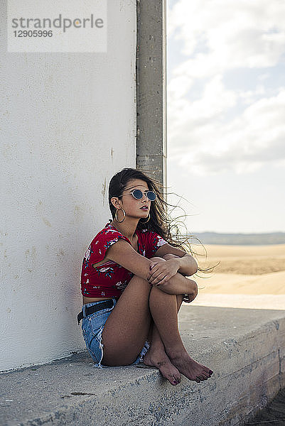Portrait of teenage girl wearing sunglasses sitting among the shades looking at distance