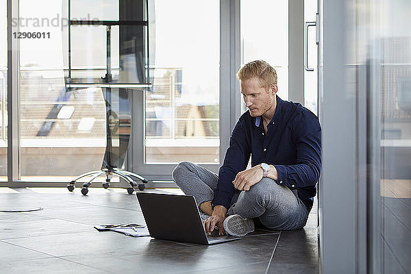 Businessman sitting on the floor using laptop