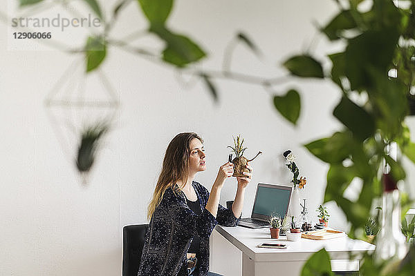 Young woman with laptop at home caring for plants