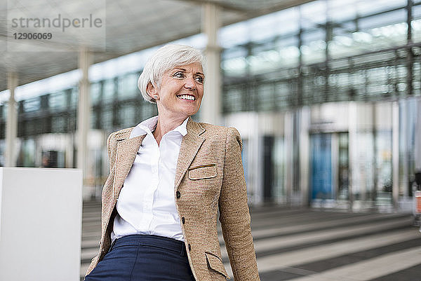 Smiling senior businesswoman sitting in the city looking around