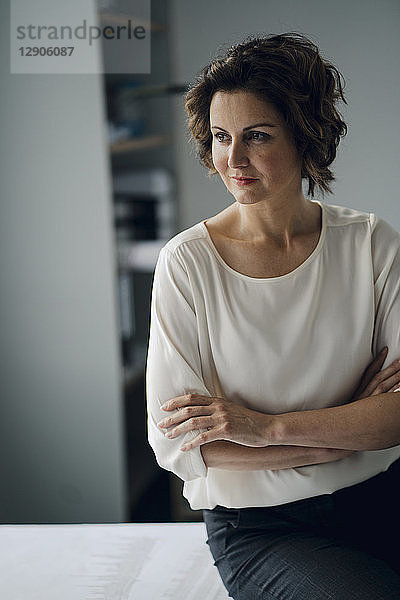 Mature businesswoman sitting in office with arms crossed