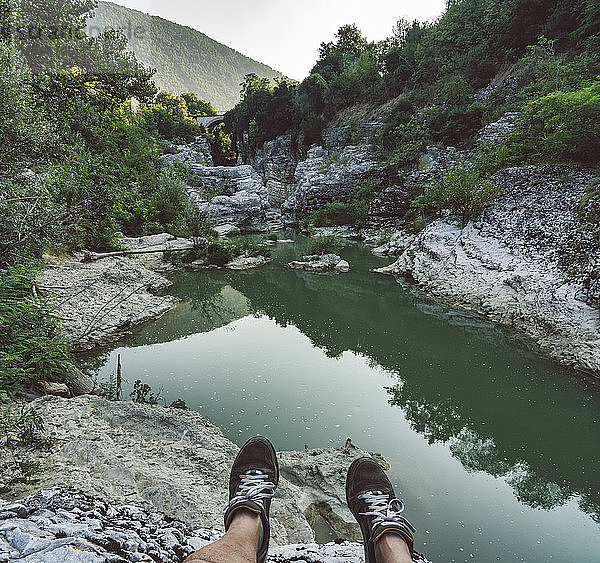 Italy  Marche  Fossombrone  Marmitte dei Giganti canyon  Metauro river  hiker sitting on riverside  shoes