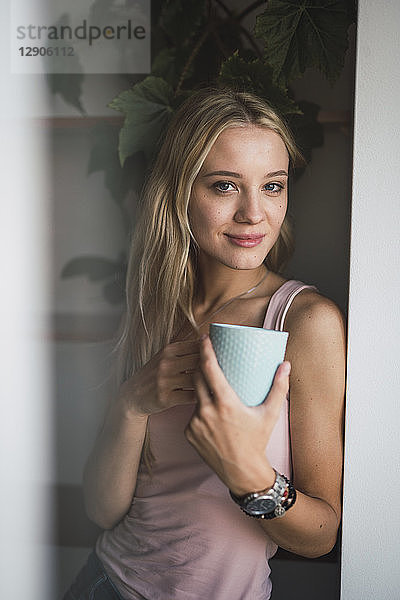 Portrait of smiling blond young woman holding coffee mug