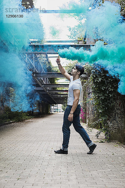 Young man walking with smoke torch outdoors