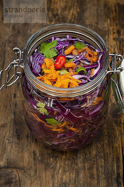 Homemade red cabbage  fermented  with chili  carrot and coriander  preserving jar on wood