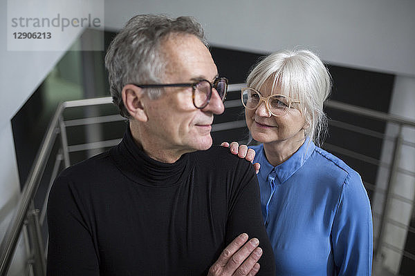 Senior woman supporting senior businessman on office stairs