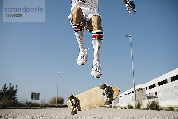Sportive man jumping above ground with skateboard performing trick