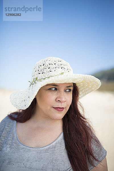 Portrait of woman wearing summer hat on the beach watching something