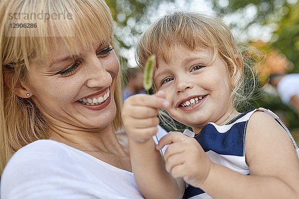 Happy mother with her daughter holding a stalk outdoors