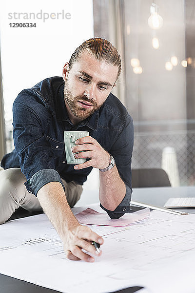 Young businessman working on plan at desk in office