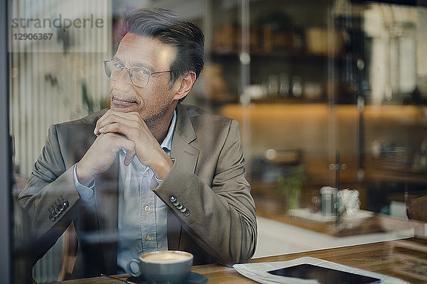 Mature businessman sitting in coffee shop  smiling