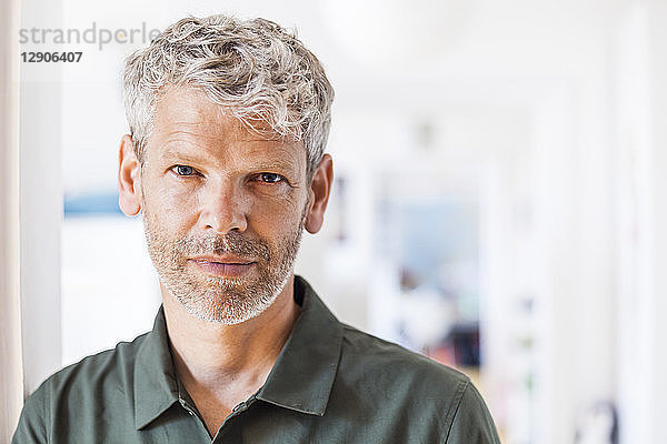 Portrait of mature man with grey hair and stubble at home