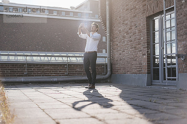 Businessman standing on rooftop terrace  taking a selfie