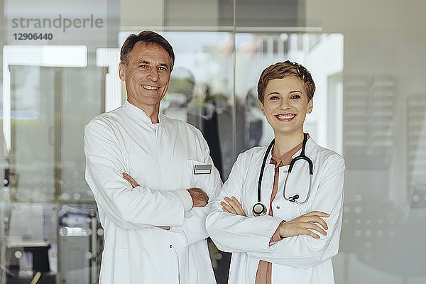 Two confident doctors standing in practice  with arms crossed