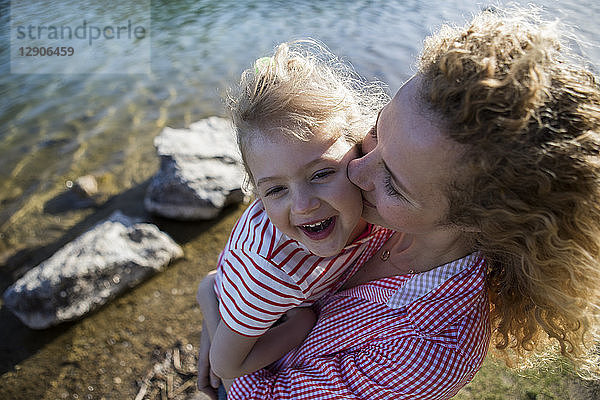 Austria  Tyrol  Walchsee  mother carrying happy daughter at the lake
